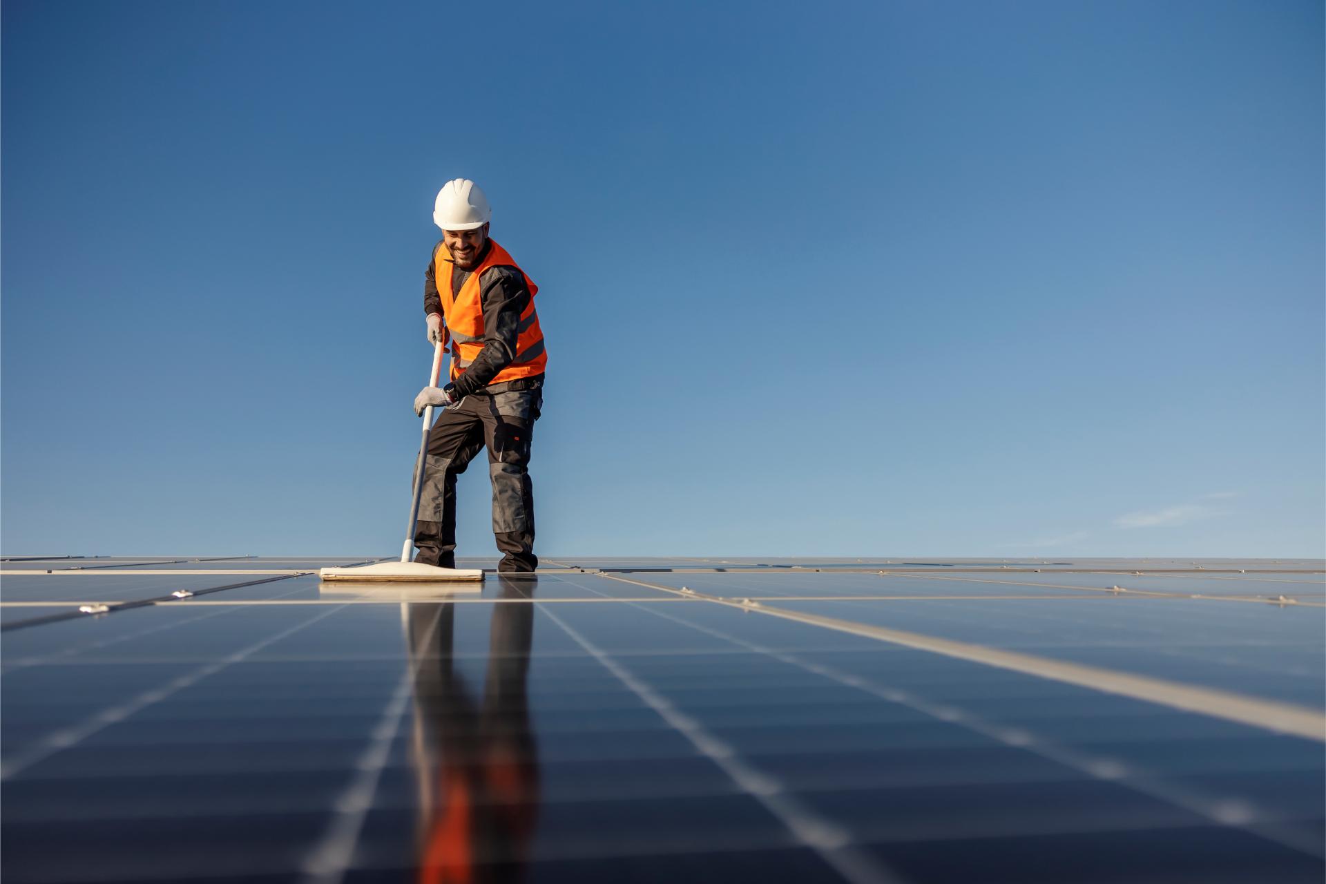 A worker is cleaning solar panels from dust